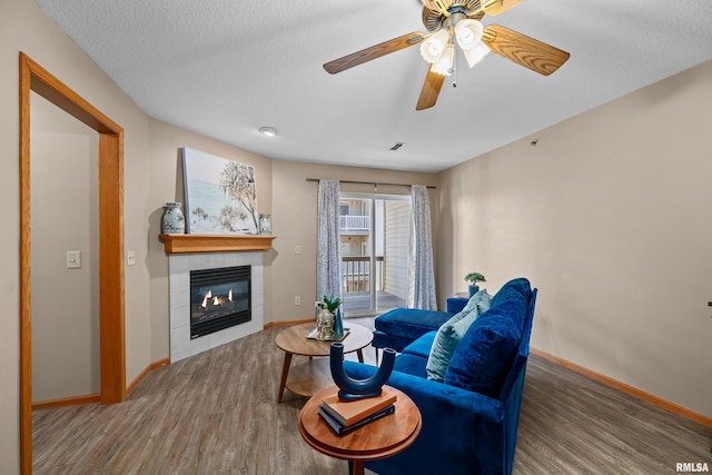 3814 Creek Hill Dr, Bettendorf, IA 52722 - living area featuring wood finished floors, baseboards, a tile fireplace, ceiling fan, and a textured ceiling