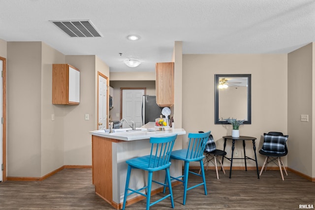 3814 Creek Hill Dr, Bettendorf, IA 52722 - kitchen with baseboards, wood finished floors, a kitchen bar, and a textured ceiling