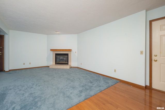 4675 Kynnelworth Dr Unit 301, Bettendorf, IA 52722 - unfurnished living room featuring a tile fireplace, baseboards, and light wood-style flooring