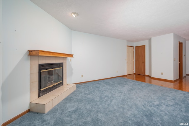 4675 Kynnelworth Dr Unit 301, Bettendorf, IA 52722 - unfurnished living room featuring a tiled fireplace, carpet, baseboards, and a textured ceiling