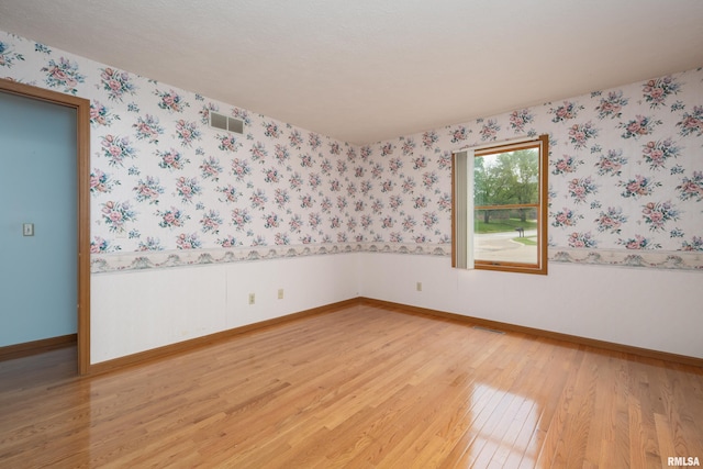 4675 Kynnelworth Dr Unit 301, Bettendorf, IA 52722 - spare room featuring light wood finished floors, wallpapered walls, baseboards, and a wainscoted wall