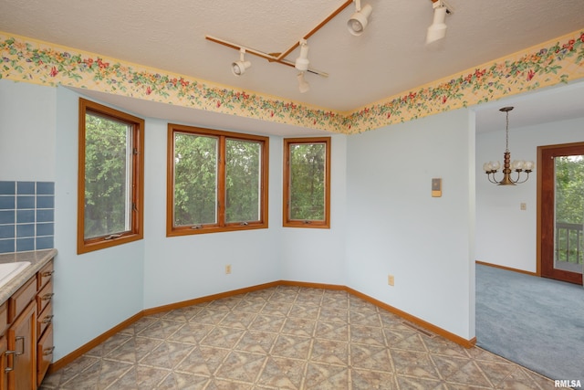 4675 Kynnelworth Dr Unit 301, Bettendorf, IA 52722 - unfurnished room with a chandelier, baseboards, track lighting, and a textured ceiling