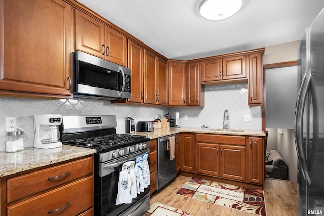 2614 W 59th St, Davenport, IA 52806 - kitchen featuring stainless steel appliances, a sink, light wood-style flooring, and brown cabinetry