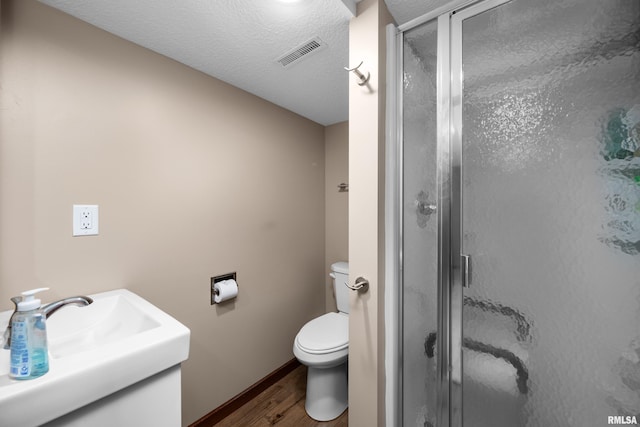 2614 W 59th St, Davenport, IA 52806 - bathroom featuring wood finished floors, a shower stall, toilet, a textured ceiling, and baseboards