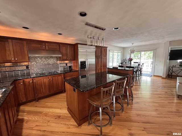 462 Circle Dr, Kewanee, IL 61443 - kitchen featuring stainless steel built in fridge, under cabinet range hood, a kitchen island, gas cooktop, and light wood-style flooring