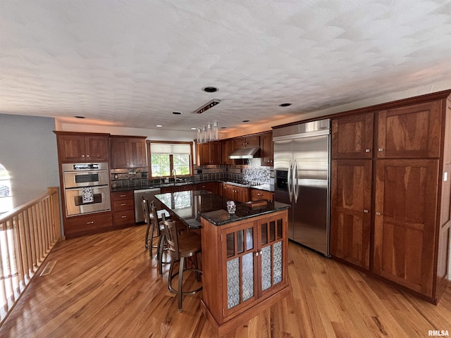 462 Circle Dr, Kewanee, IL 61443 - kitchen featuring appliances with stainless steel finishes, under cabinet range hood, light wood-type flooring, a sink, and backsplash