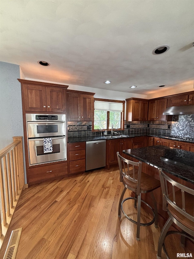 462 Circle Dr, Kewanee, IL 61443 - kitchen with stainless steel appliances, backsplash, light wood-style floors, a sink, and under cabinet range hood