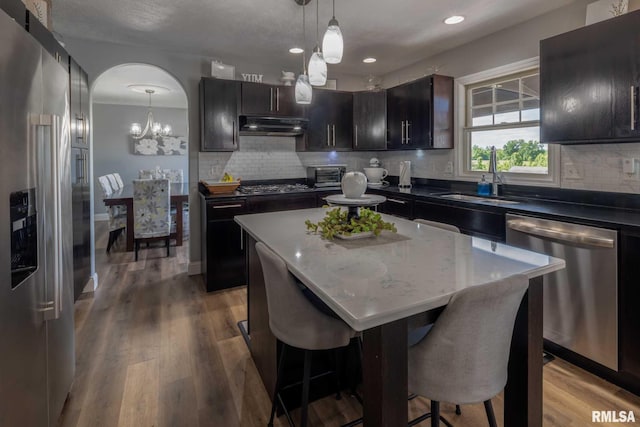 3160 Sycamore Rd, Carterville, IL 62918 - kitchen featuring appliances with stainless steel finishes, a sink, under cabinet range hood, arched walkways, and a kitchen bar