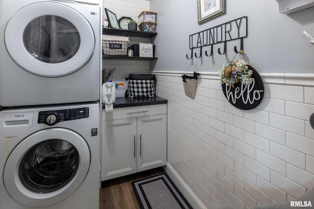 3160 Sycamore Rd, Carterville, IL 62918 - washroom with stacked washing machine and dryer, cabinet space, dark wood-style flooring, tile walls, and wainscoting