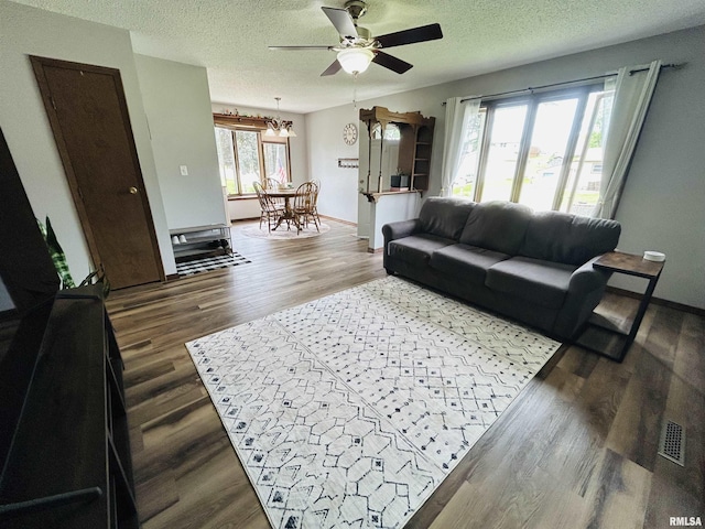 709S 4th St S, Maquoketa, IA 52060 - living area with ceiling fan, a textured ceiling, dark wood-style flooring, baseboards, and a chandelier