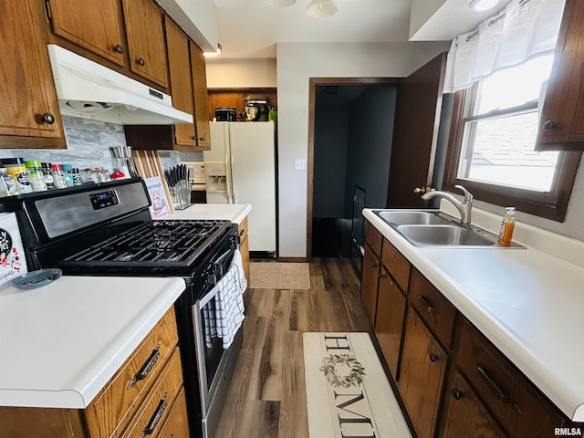 709S 4th St S, Maquoketa, IA 52060 - kitchen with stainless steel range with gas cooktop, under cabinet range hood, a sink, white fridge with ice dispenser, and dark wood-type flooring