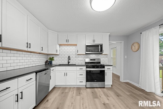 1156 23rd St, Moline, IL 61265 - kitchen featuring stainless steel appliances, tasteful backsplash, light wood-type flooring, white cabinets, and dark countertops