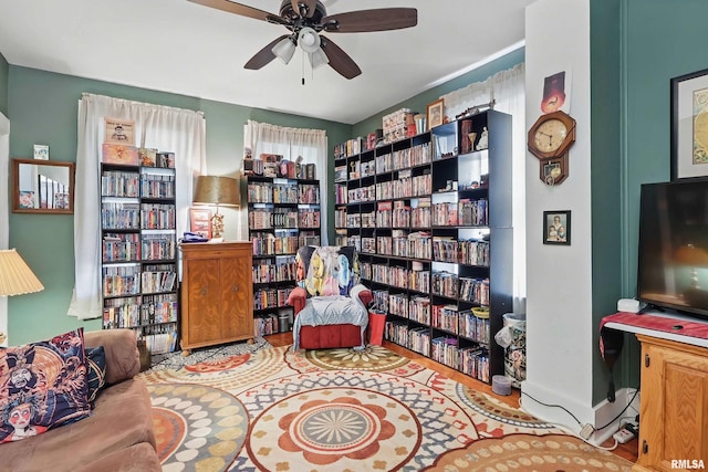 1931 E 11th St, Davenport, IA 52803 - living area featuring wall of books, ceiling fan, wood finished floors, and baseboards