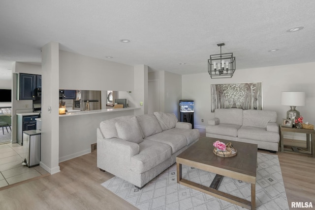 28013 230th St, Le Claire, IA 52753 - living room featuring light wood-type flooring, a chandelier, recessed lighting, a textured ceiling, and baseboards