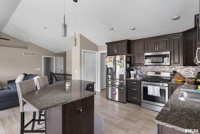 1625 W 71st St, Davenport, IA 52806 - kitchen with stainless steel appliances, open floor plan, lofted ceiling, a breakfast bar area, and tasteful backsplash