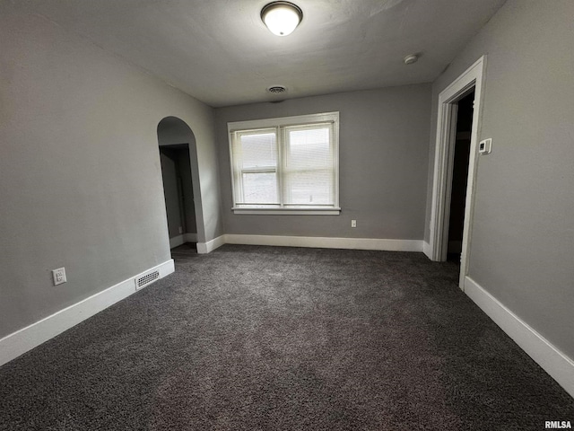 2107 N Marquette St, Davenport, IA 52804 - empty room featuring arched walkways, dark colored carpet, and baseboards