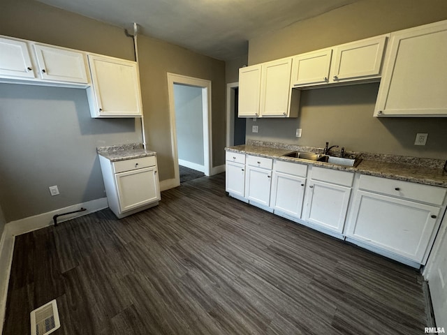 2107 N Marquette St, Davenport, IA 52804 - kitchen with a sink, white cabinetry, baseboards, and dark wood finished floors