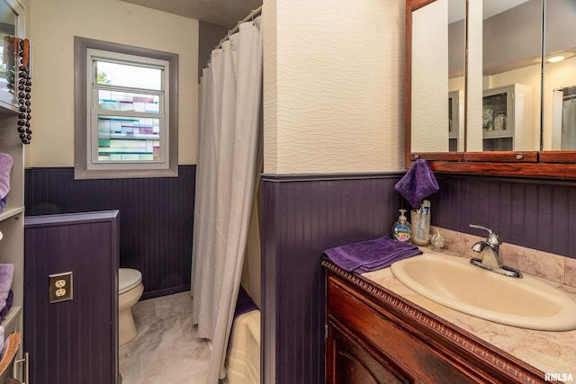 615 W Grand Ave, Carterville, IL 62918 - bathroom featuring a wainscoted wall, toilet, vanity, marble look tiles, and shower / bathtub combination with curtain