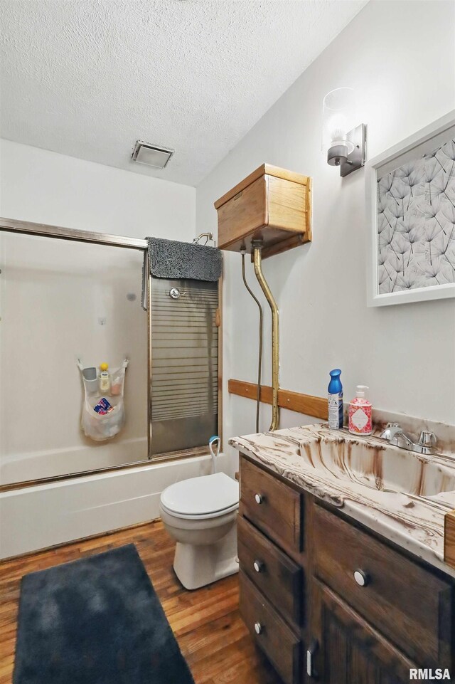 3414 Fillmore Ln, Davenport, IA 52806 - full bathroom with wood finished floors, vanity, bath / shower combo with glass door, toilet, and a textured ceiling