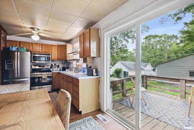 3414 Fillmore Ln, Davenport, IA 52806 - kitchen with appliances with stainless steel finishes, light countertops, wood finished floors, a sink, and brown cabinets