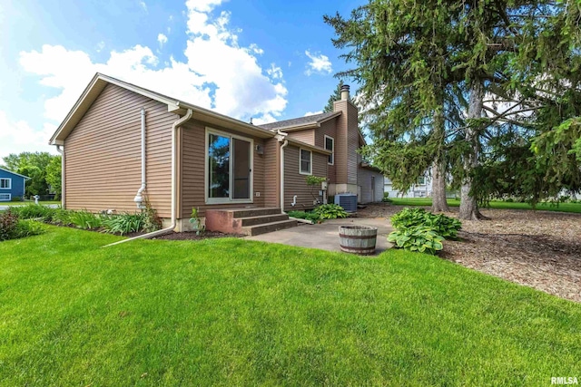 3845 Norwich Ct, Bettendorf, IA 52722 - back of house with central air condition unit, a chimney, a yard, an outdoor fire pit, and a patio