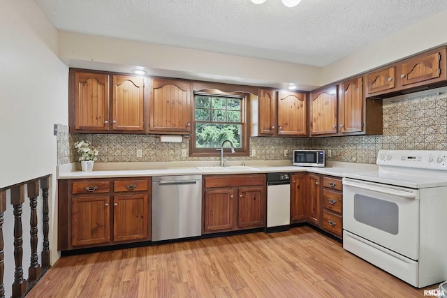 3845 Norwich Ct, Bettendorf, IA 52722 - kitchen featuring stainless steel appliances, a sink, light wood-type flooring, light countertops, and a textured ceiling