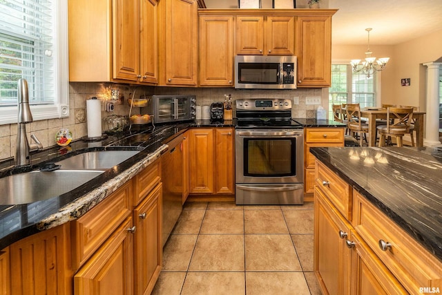 1404 Belle Terre Ct, Herrin, IL 62948 - kitchen featuring appliances with stainless steel finishes, a sink, brown cabinetry, a chandelier, and tasteful backsplash