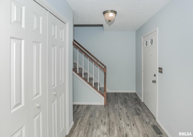 4760 Apple Valley Dr, Bettendorf, IA 52722 - foyer entrance featuring wood finished floors, stairway, a textured ceiling, and baseboards