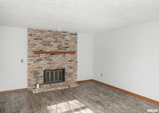 4760 Apple Valley Dr, Bettendorf, IA 52722 - unfurnished living room featuring a brick fireplace, wood finished floors, a textured ceiling, and baseboards