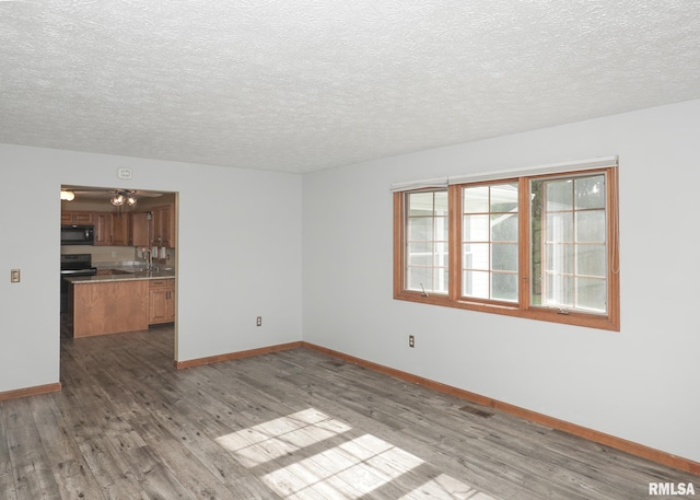 4760 Apple Valley Dr, Bettendorf, IA 52722 - spare room with wood finished floors, baseboards, a textured ceiling, and a sink