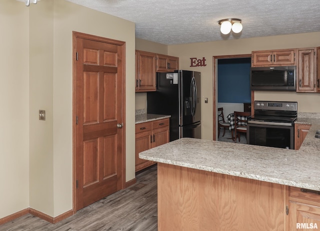4760 Apple Valley Dr, Bettendorf, IA 52722 - kitchen featuring appliances with stainless steel finishes, wood finished floors, a peninsula, baseboards, and a textured ceiling