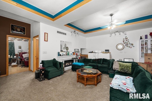 911 Cardinal Dr, Maquoketa, IA 52060 - living room featuring carpet floors, a ceiling fan, a lit fireplace, and a tray ceiling