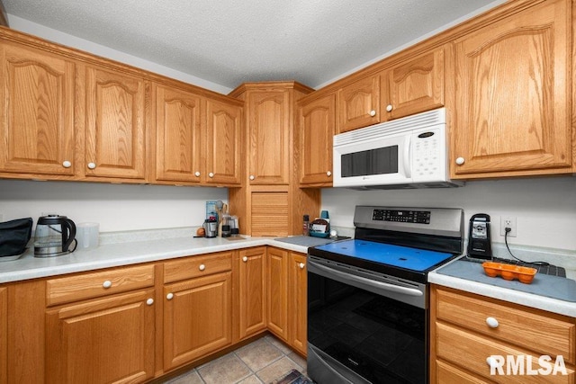 911 Cardinal Dr, Maquoketa, IA 52060 - kitchen featuring stainless steel electric stove, white microwave, light countertops, light tile patterned flooring, and brown cabinetry