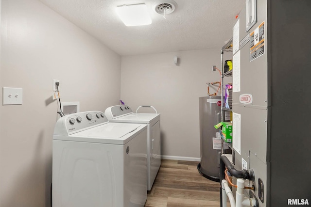 404 S 23rd St, Herrin, IL 62948 - laundry area featuring washer and clothes dryer, heating unit, light wood-style floors, electric water heater, and a textured ceiling