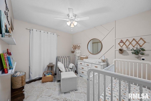 5647 Quercus Ln, Davenport, IA 52806 - bedroom featuring a crib, a textured ceiling, and a ceiling fan