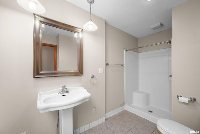 2920 Roosevelt St, Clinton, IA 52732 - bathroom with tile patterned floors, baseboards, toilet, a shower, and a textured ceiling