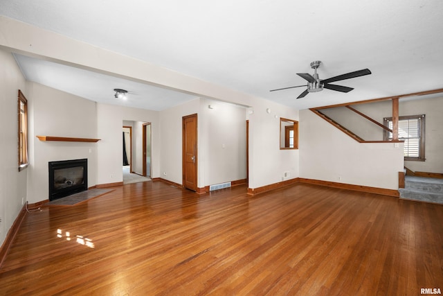 2920 Roosevelt St, Clinton, IA 52732 - unfurnished living room featuring wood finished floors, a ceiling fan, a fireplace with flush hearth, and baseboards