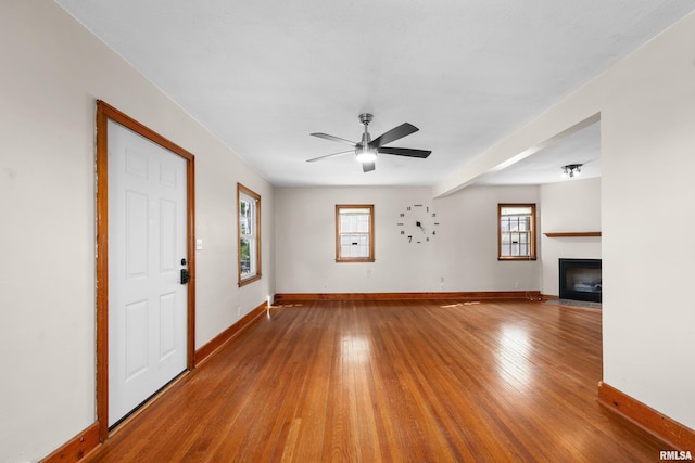 2920 Roosevelt St, Clinton, IA 52732 - unfurnished living room with wood finished floors, baseboards, ceiling fan, and a fireplace with flush hearth