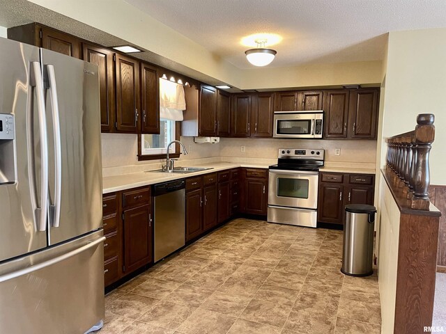 201 S Herrmann Dr, Ridgway, IL 62979 - kitchen featuring stainless steel appliances, a sink, light countertops, dark brown cabinetry, and a textured ceiling