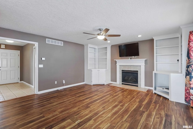 108 N Howard Ln, Long Grove, IA 52756 - unfurnished living room with a ceiling fan, wood finished floors, a textured ceiling, a fireplace, and built in features