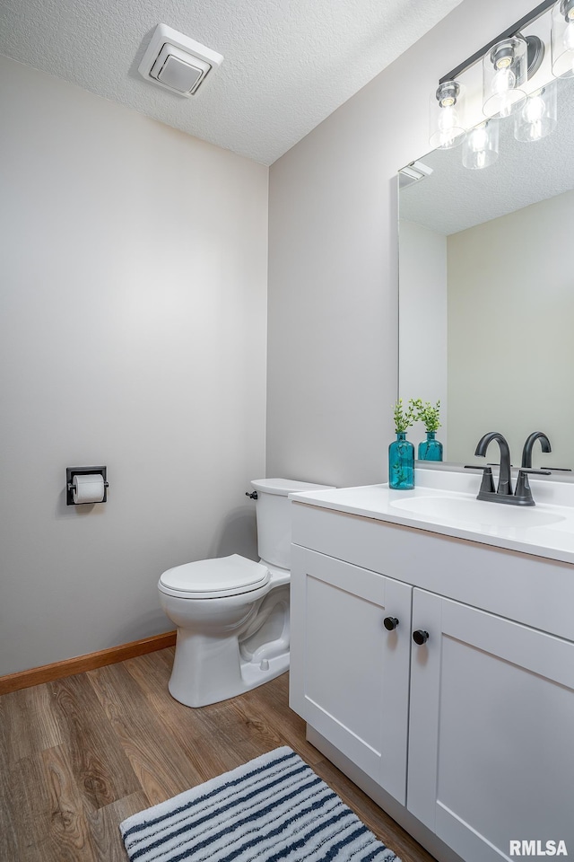 4260 Sapphire Ln, Bettendorf, IA 52722 - half bath with toilet, vanity, wood finished floors, and a textured ceiling