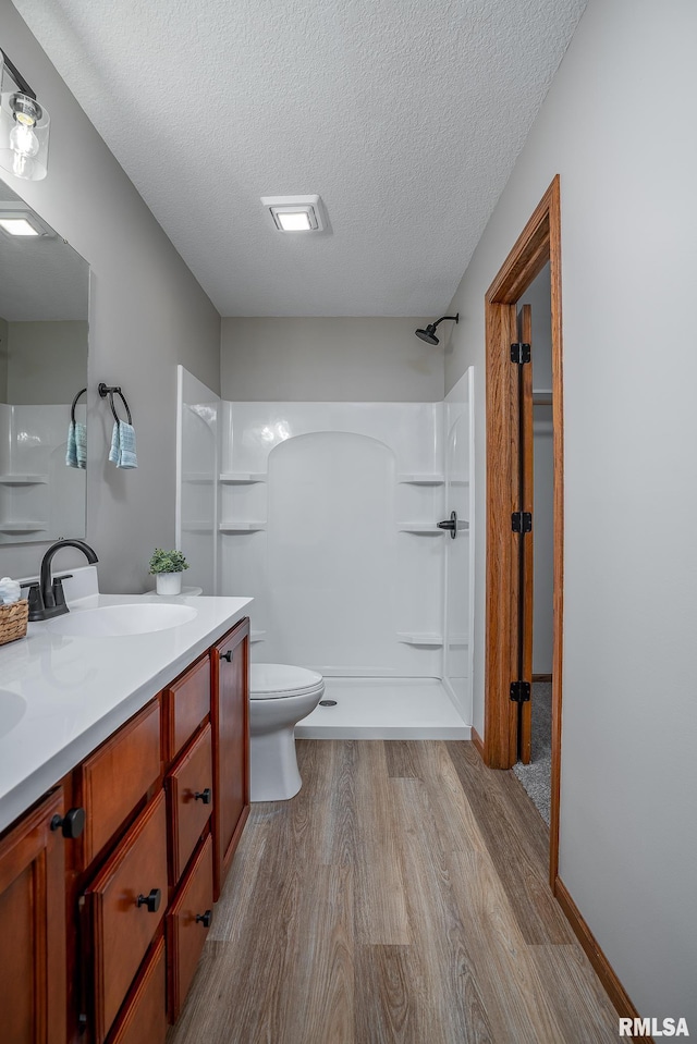 4260 Sapphire Ln, Bettendorf, IA 52722 - bathroom featuring wood finished floors, vanity, a shower, a textured ceiling, and toilet