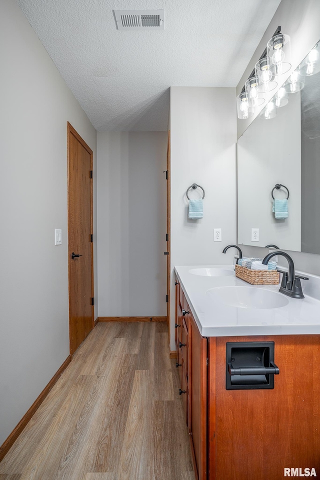4260 Sapphire Ln, Bettendorf, IA 52722 - bathroom with wood finished floors, double vanity, a textured ceiling, and baseboards