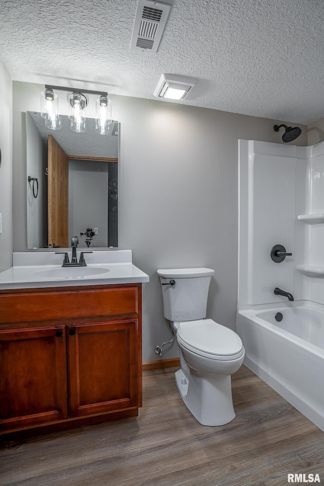 4260 Sapphire Ln, Bettendorf, IA 52722 - bathroom featuring vanity, toilet, wood finished floors, bathtub / shower combination, and a textured ceiling
