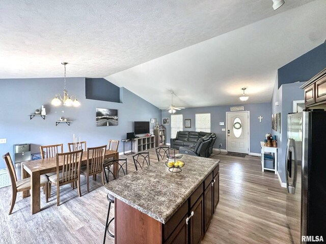 203 Breeze Dr, Carterville, IL 62918 - kitchen featuring freestanding refrigerator, light wood-style flooring, a breakfast bar, ceiling fan, and vaulted ceiling