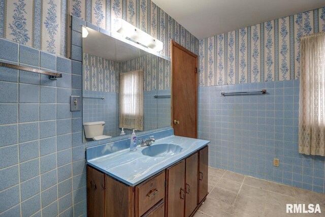 1148 Briarcliff Ln, Clinton, IA 52732 - bathroom featuring tile walls, tile patterned floors, vanity, wallpapered walls, and a wainscoted wall