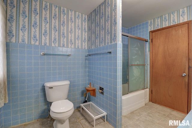 1148 Briarcliff Ln, Clinton, IA 52732 - full bath featuring wallpapered walls, toilet, tile walls, bath / shower combo with glass door, and tile patterned floors