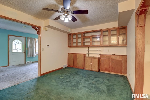 1148 Briarcliff Ln, Clinton, IA 52732 - kitchen with dark colored carpet, brown cabinetry, a textured ceiling, a ceiling fan, and glass insert cabinets