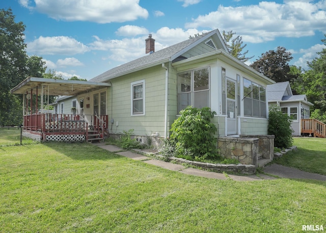 1036 30th St, Rock Island, IL 61201 - view of home's exterior featuring a sunroom, a chimney, a wooden deck, a lawn, and roof with shingles