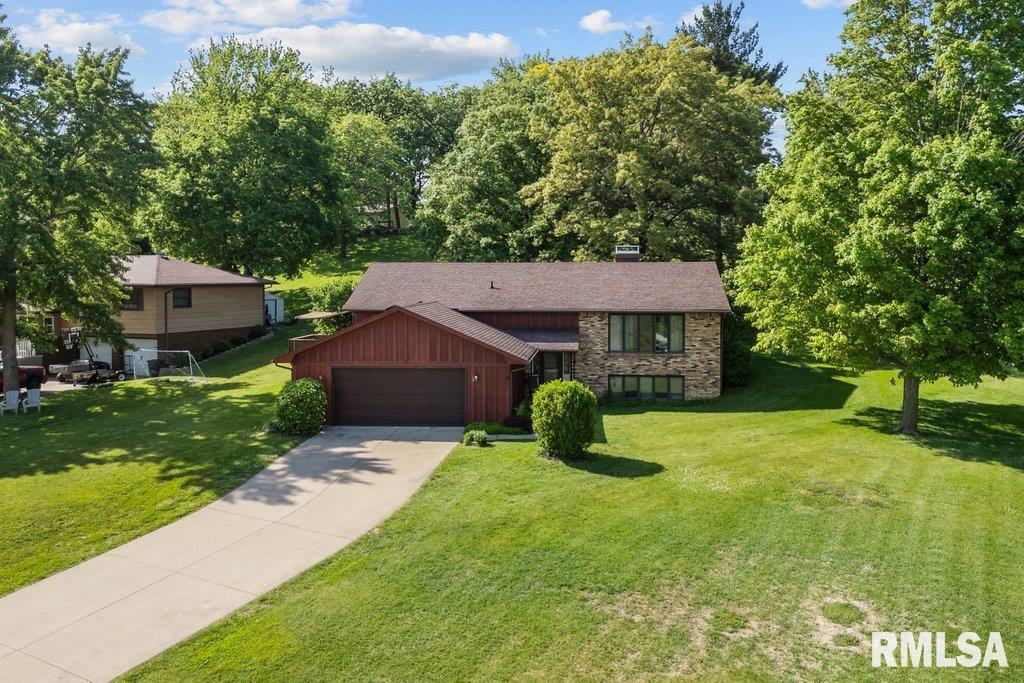 440 Center Dr, Geneseo, IL 61254 - view of front facade featuring a garage, concrete driveway, board and batten siding, a front lawn, and stone siding